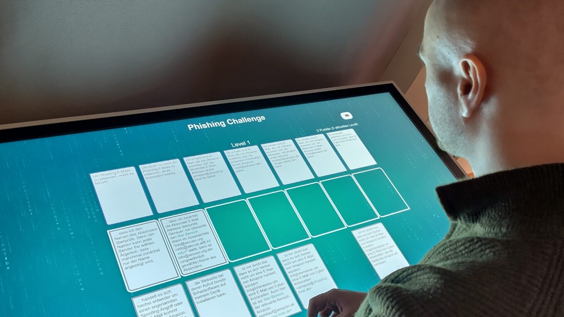 Ein Mann spielt das digitale NoPhish-Kartenspiel an einem Touchscreen.