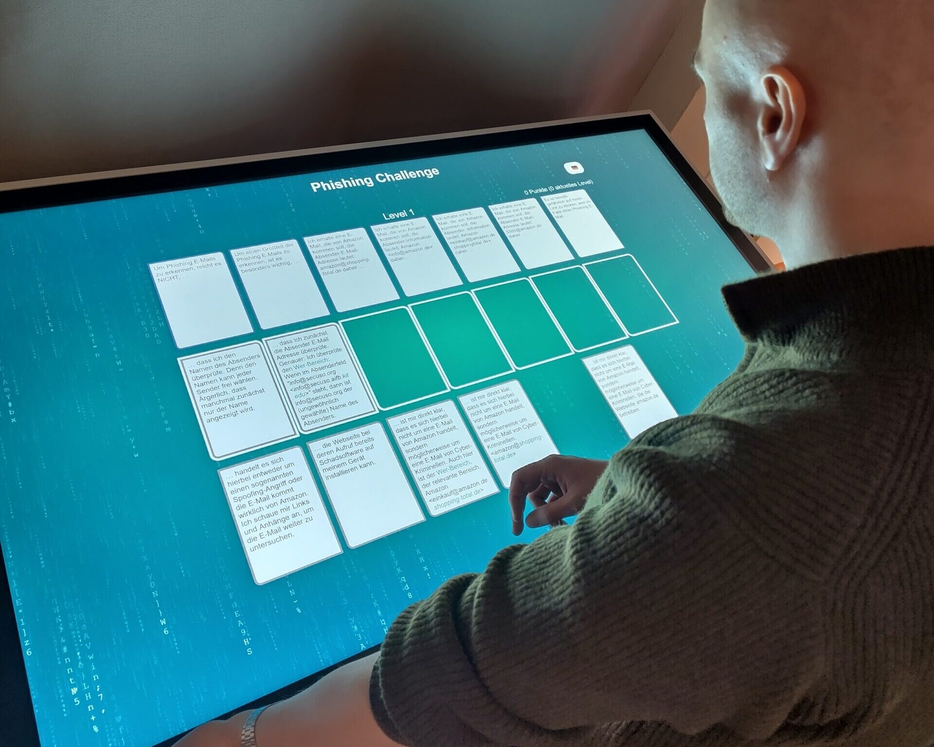 Ein Mann spielt das digitale NoPhish-Kartenspiel an einem Touchscreen.