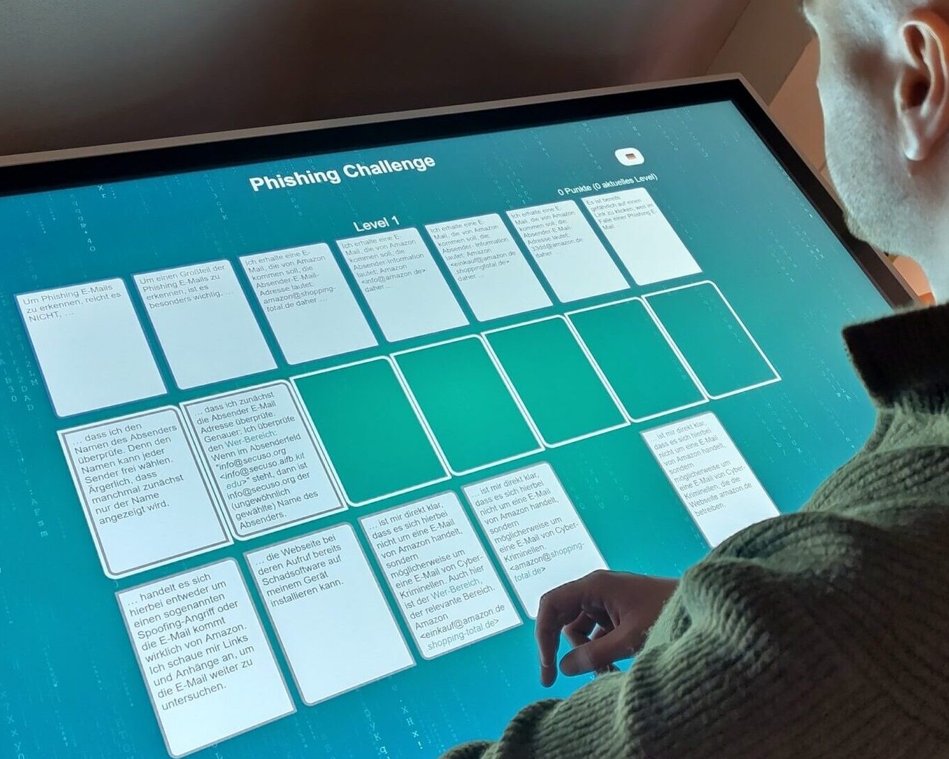 Ein Mann spielt das digitale NoPhish-Kartenspiel an einem Touchscreen.