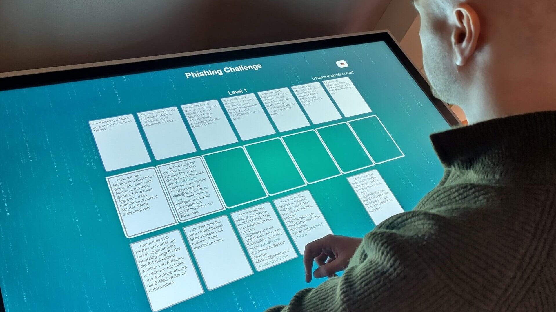 Ein Mann spielt das digitale NoPhish-Kartenspiel an einem Touchscreen.